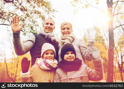 family, childhood, season, gesture and people concept - happy family waving hands in autumn park