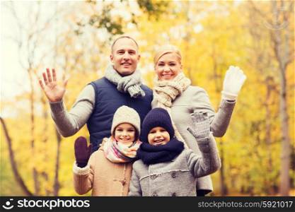 family, childhood, season, gesture and people concept - happy family waving hands in autumn park