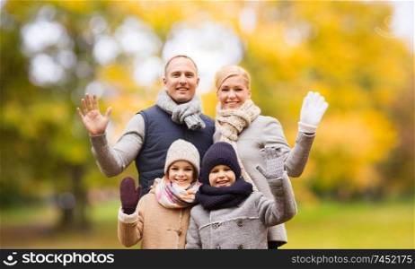 family, childhood, season, gesture and people concept - happy family waving hands in autumn park. happy family in autumn park