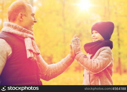 family, childhood, season, gesture and people concept - happy father and son making high five in autumn park