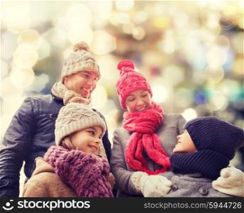 family, childhood, season, holidays and people concept - happy family in winter clothes over lights background