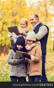 family, childhood, season, technology and people concept - happy family with tablet pc computers in autumn park