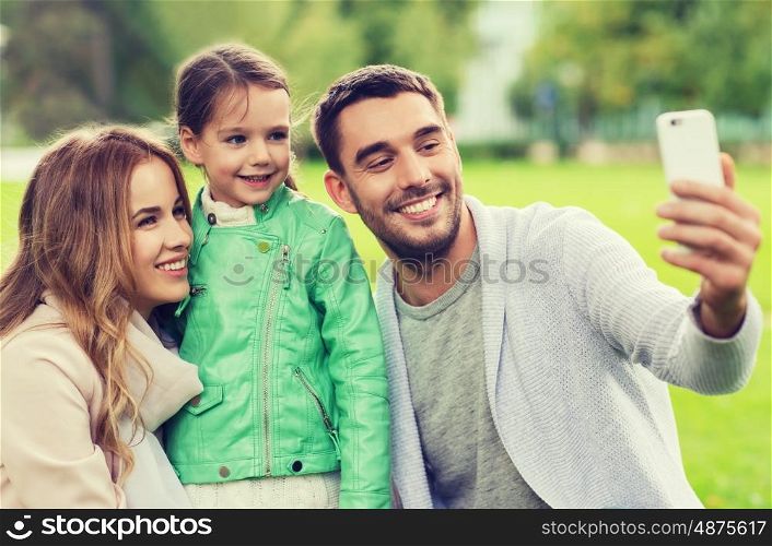 family, childhood, technology and people concept - happy family taking selfie by smartphone in park