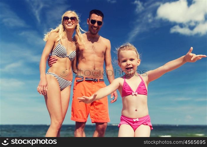 family, childhood, travel and people concept - close up of happy man, woman and little girl having fun on summer beach
