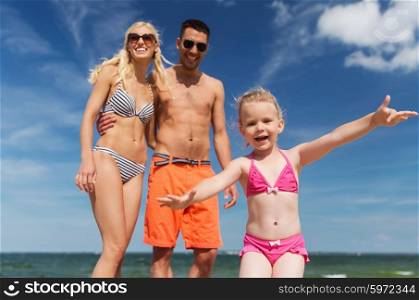 family, childhood, travel and people concept - close up of happy man, woman and little girl having fun on summer beach