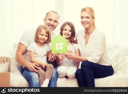 family, children, accomodation and home concept - smiling parents and two little girls holding green house
