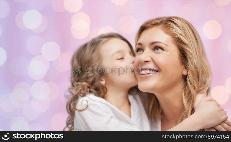 family, children and happy people concept - happy little girl hugging and kissing her mother over pink holidays lights background