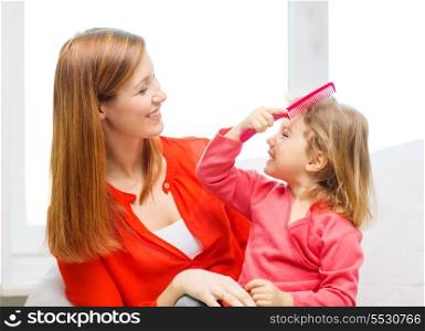 family, children and happy people concept - happy mother and daughter with pink comb