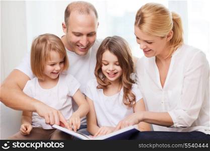 family, children and home concept - smiling family and two little girls with book at home