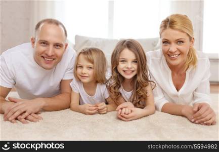 family, children and home concept - smiling family with and two little girls lying on floor at home