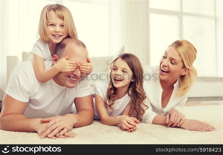 family, children and home concept - smiling family with and two little girls lying on floor at home and having fun