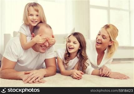family, children and home concept - smiling family with and two little girls lying on floor at home and having fun