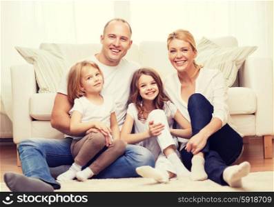 family, children and home concept - smiling family with and two little girls sitting on floor at home