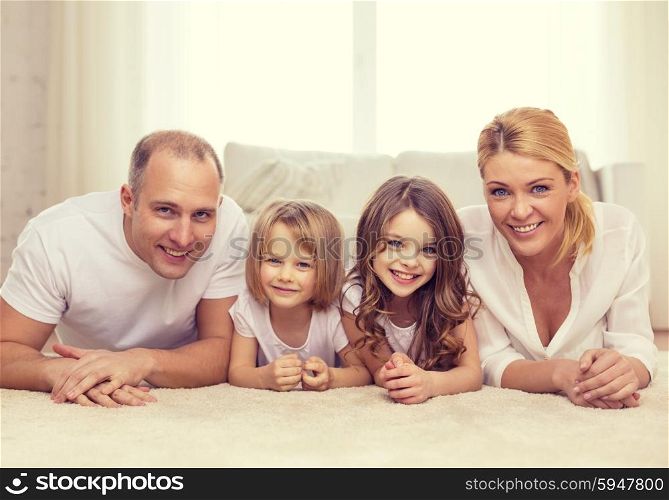 family, children and home concept - smiling family with and two little girls lying on floor at home