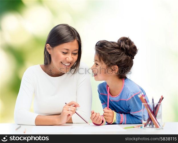 family, children and people concept - happy mother and daughter drawing and talking over green background