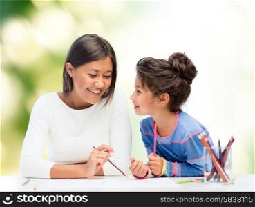 family, children and people concept - happy mother and daughter drawing and talking over green background