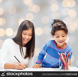 family, children and people concept - happy mother and daughter drawing over holidays lights background