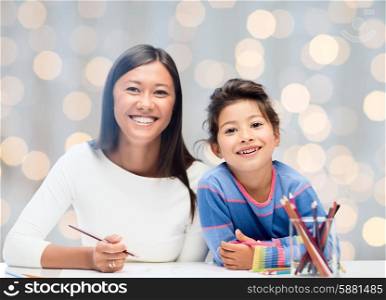 family, children and people concept - happy mother and daughter drawing over holidays lights background