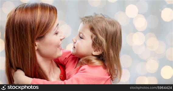 family, children and people concept - happy mother and little daughter hugging over holidays lights background