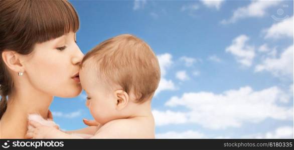 family, children and people concept - happy mother kissing baby boy over blue sky and clouds background