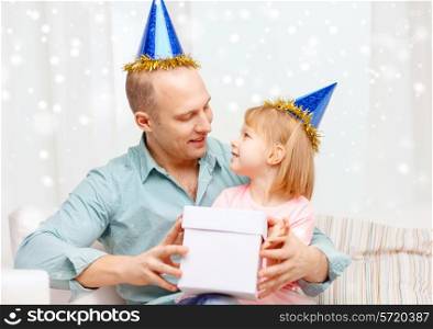 family, children, celebration, holidays and happy people concept - happy father and daughter in party caps with gift box