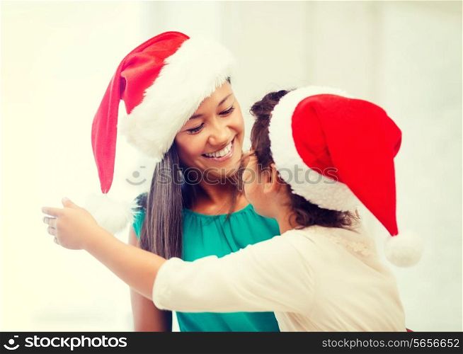 family, children, christmas and happy people concept - hugging mother and daughter in santa helper hats