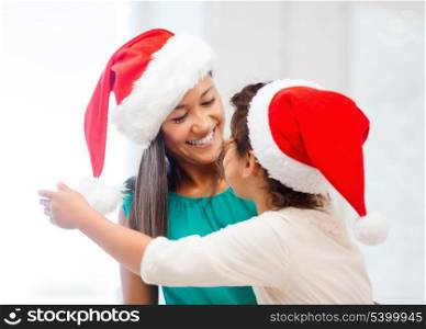family, children, christmas, x-mas and happy people concept - hugging mother and daughter in santa helper hats