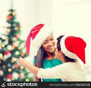 family, children, christmas, x-mas and happy people concept - hugging mother and daughter in santa helper hats