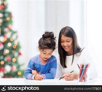 family, children, christmas, x-mas and happy people concept - mother and daughter drawing