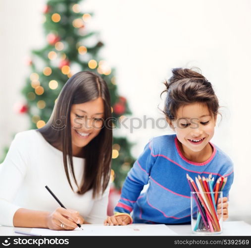 family, children, christmas, x-mas and happy people concept - mother and daughter drawing