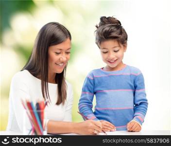 family, children, creativity and happy people concept - happy mother and daughter drawing with pencils over green background