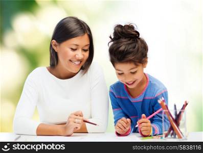 family, children, creativity and happy people concept - happy mother and daughter drawing with pencils over green background