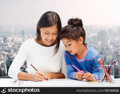 family, children, creativity and happy people concept - happy mother and daughter drawing with pencils over city background