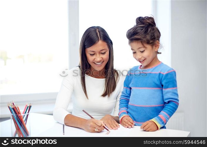 family, children, creativity and happy people concept - happy mother and daughter drawing with pencils at home or kindergarten