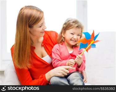 family, children, ecology and happy people concept - happy mother and daughter with pinwheel toy
