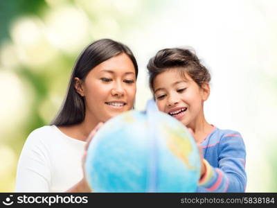 family, children, education, geography and people concept - happy mother and daughter with globe over green background