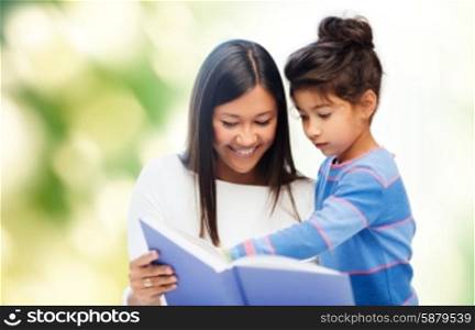 family, children, education, school and happy people concept - happy mother and daughter reading book over green background
