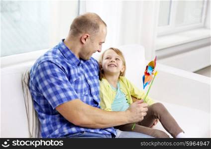family, children, fathers day and parenthood people concept - happy father and daughter sitting on sofa at home