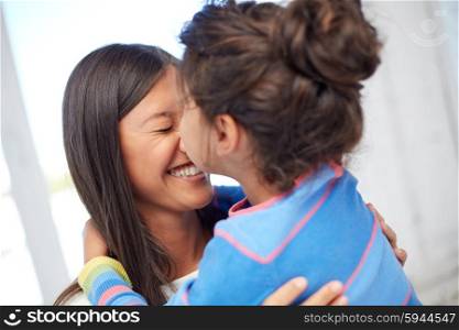 family, children, love and happy people concept - happy little girl hugging mother and kissing her on nose at home