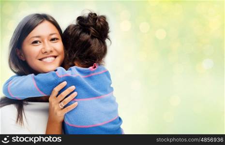 family, children, love and happy people concept - happy mother and daughter hugging over green holidays lights background