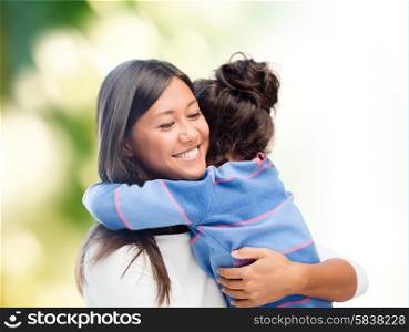 family, children, love and happy people concept - happy mother and daughter hugging over green background