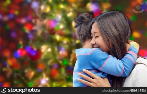family, children, love and happy people concept - happy mother and daughter hugging over lights background