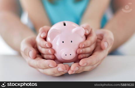 family, children, money, investments and people concept - close up of father and daughter hands holding pink piggy bank