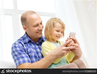 family, children, parenthood, technology and internet concept - happy father and daughter with smartphone at home