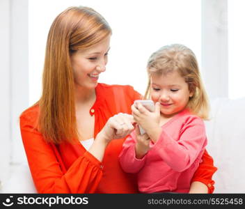 family, children, parenthood, technology and internet concept - happy mother and daughter with smartphone at home