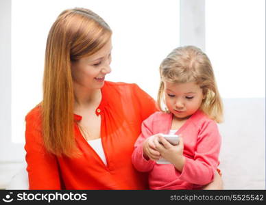 family, children, parenthood, technology and internet concept - happy mother and daughter with smartphone at home