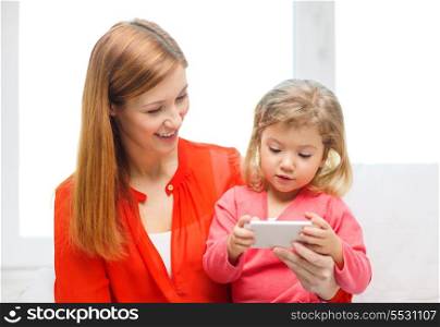 family, children, parenthood, technology and internet concept - happy mother and daughter with smartphone at home