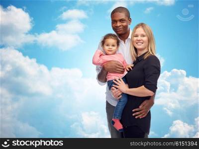 family, children, race and nationality concept - happy multiracial mother, father and little child over blue sky and clouds background