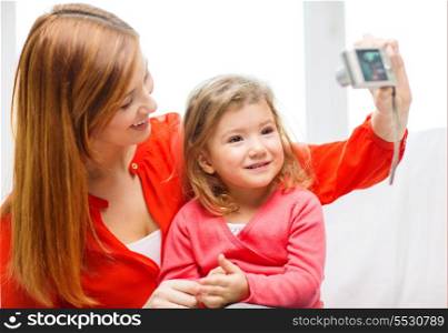 family, children, technology and happy people concept - smiling mother and daughter with digital camera