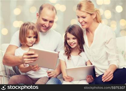 family, children, technology and people concept - smiling parents and two little girls with tablet pc computers over holidays lights background